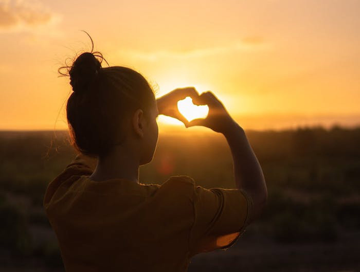 woman making sunset heart with hands