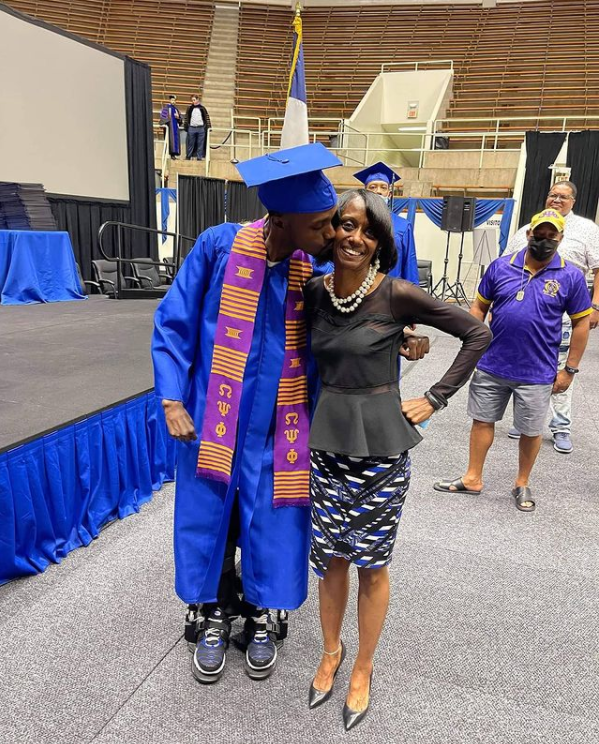 man in graduation cap and gown kissing woman on cheek