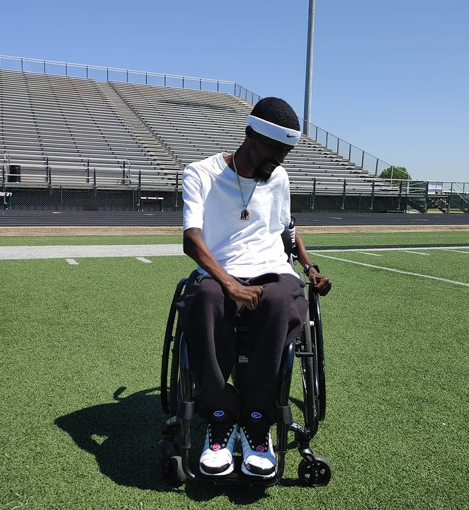 man sitting in wheelchair on football field