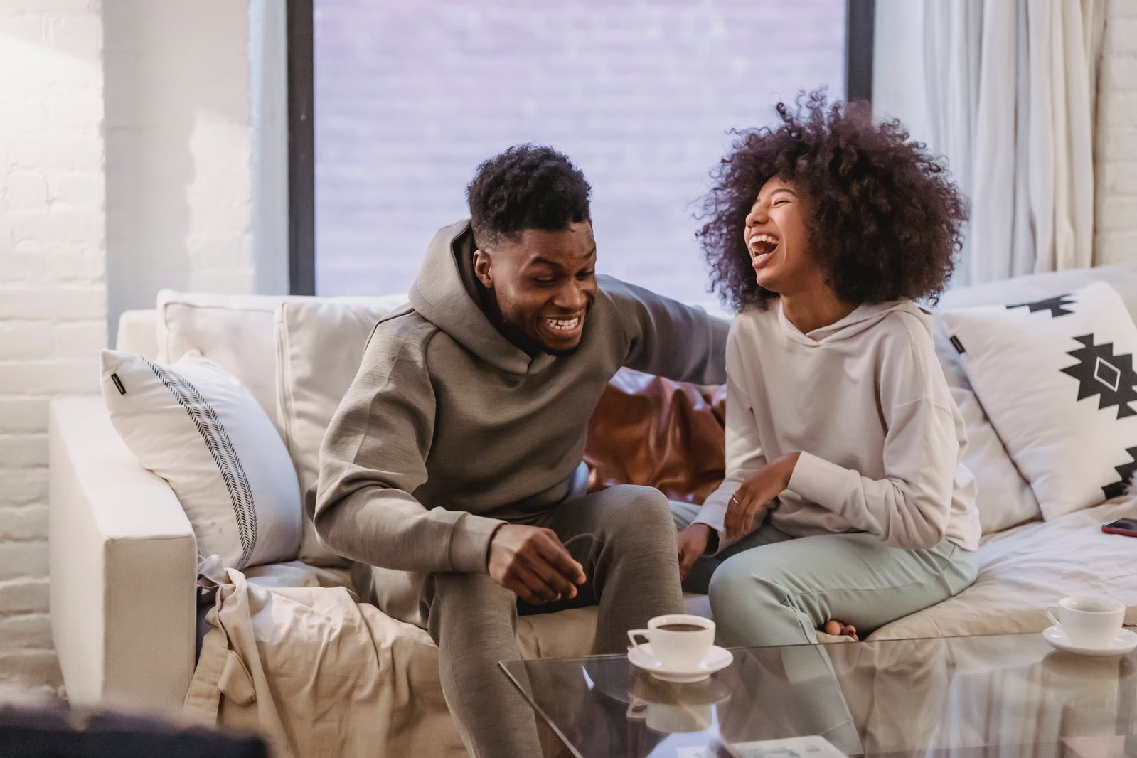 man and woman laughing on the couch