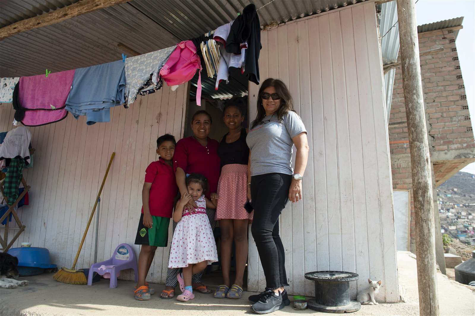 maria kristhell, her mom, and two siblings smiling and posing with a smile train partner outside of their home.