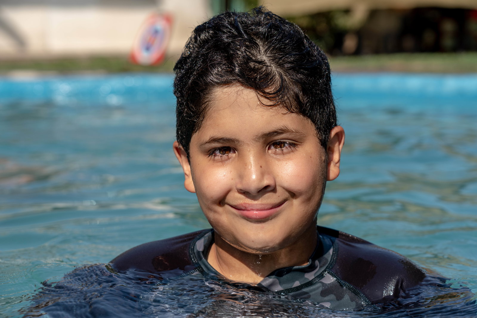 closeup of juan smiling as he wades in an outdoor pool.
