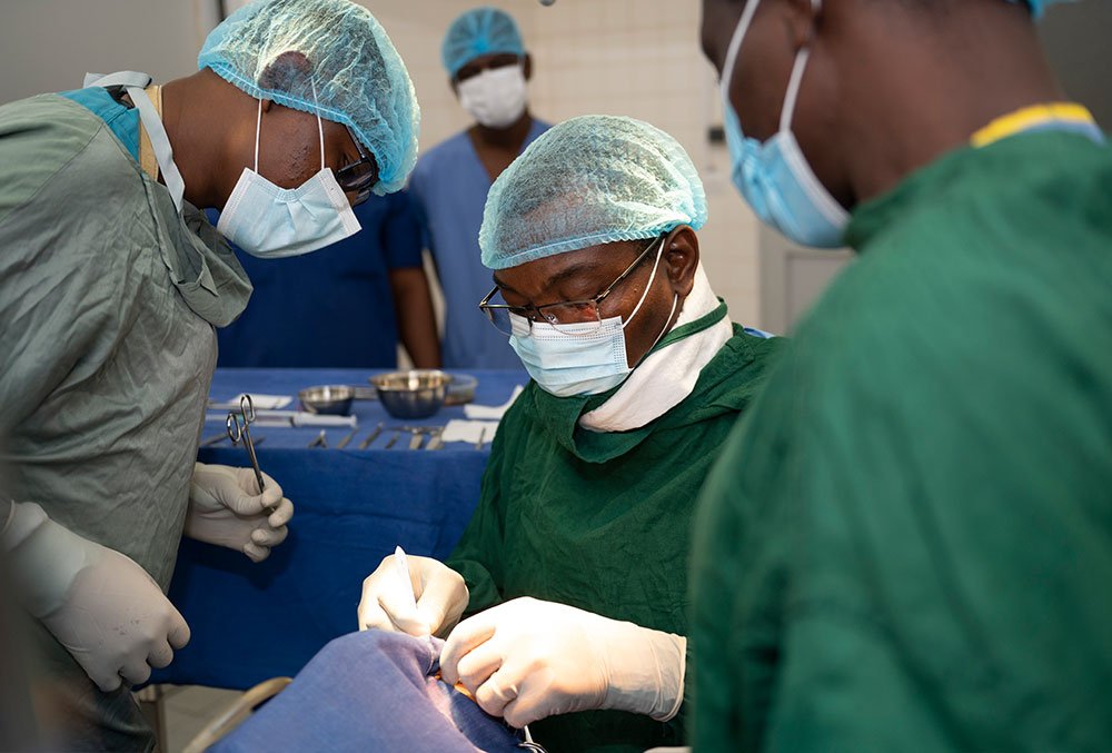 Dr. GrÃ©goire Akakpo-Numado performing cleft surgery while two other medical professionals help.