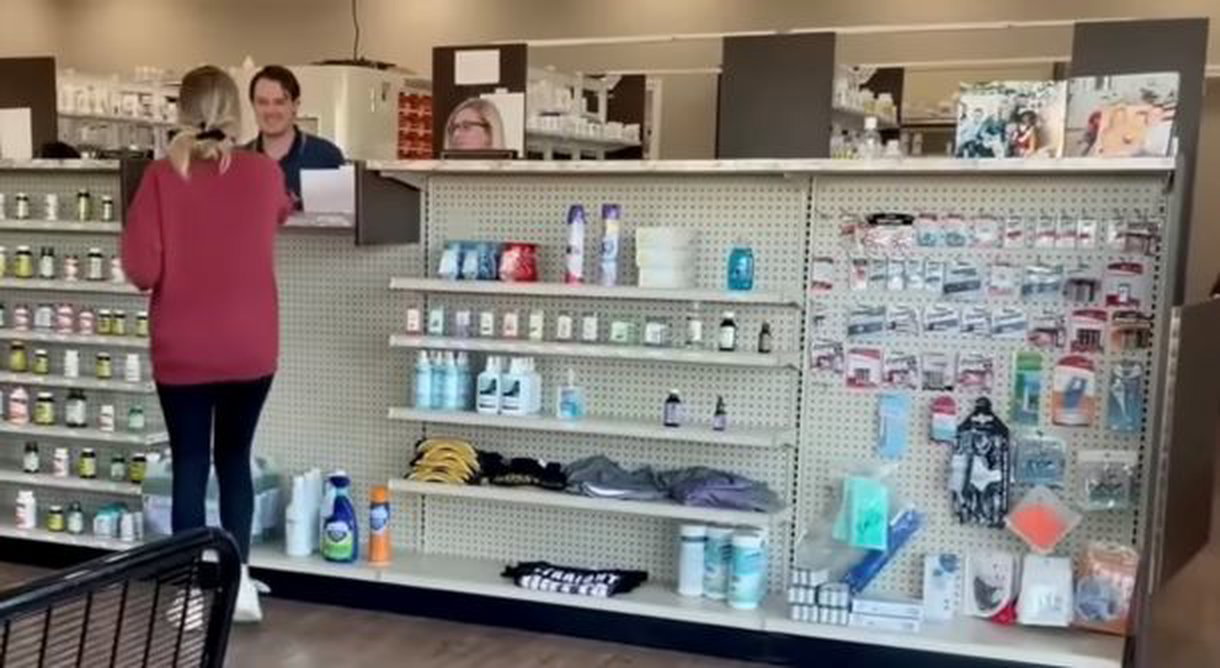 A woman is standing at the counter inside a drugstore.
