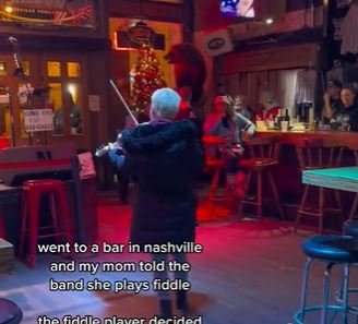 A mom playing a fiddle in a bar in Nashville with the caption "went to a bar in nashville and my mom told the band she plays fiddle."